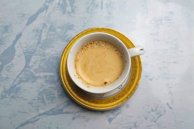 Beyaz bir masada beyaz bardakta sütlü kahve içilmeye hazır.