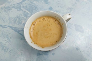 Beyaz bir masada beyaz bardakta sütlü kahve içilmeye hazır.