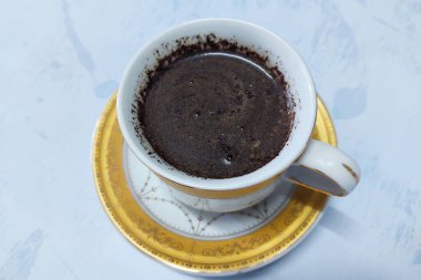 Beyaz bir masada beyaz bardakta sade kahve içilmeye hazır.