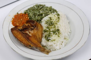 Endonezya karışık pilavı ya da yabancı balıkla karışık pirinç, tatlı patates yaprağı sebzesi ve beyaz tabakta acı sos.