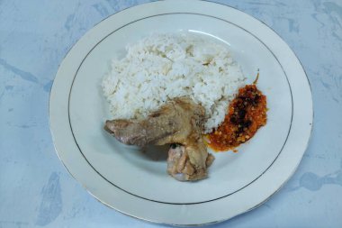 Kızarmış balık ve sebzelerle karıştırılmış pirinç beyaz bir tabakta, masanın üstünde.