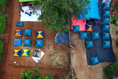 Kampın en üst manzarası koni şeklindeki çadırlar ve yeşil ağaçlarla kaplı.