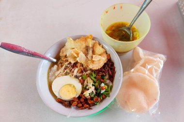 Bubur Ayam, beyaz pirinç lapası, doğranmış tavuk, kek, soya fasulyesi, kraker, yeşil soğan ve yumurtadan oluşan geleneksel bir Endonezya yemeği..