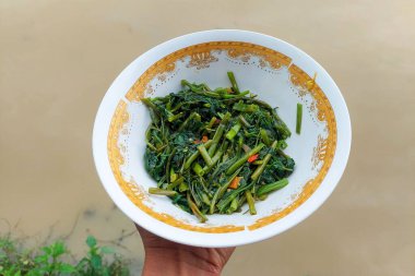 Kızarmış lahana sebzeleri pirinç tarlası arka planında beyaz bir kasede.