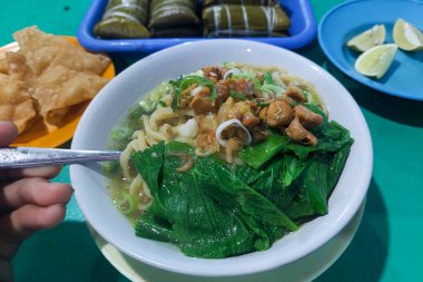 Endonezya yemekleri - Pangsip erişteleri, krakerler, buralar ve portakallar yemek masasında.