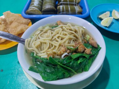 Endonezya yemekleri - Pangsip erişteleri, krakerler, buralar ve portakallar yemek masasında.