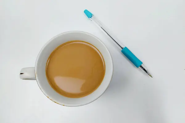 milk coffee and a pen on a white table, the coffee is ready to drink