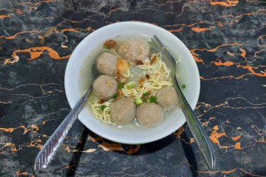 Masadaki beyaz kasede köfteli erişte.