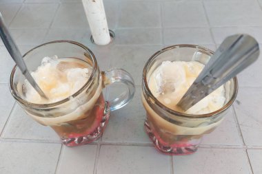 Cam bardaklarda buz ve yemek masasında kaşıklar.