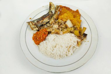 Kızarmış balık ve sebzelerle karıştırılmış pirinç beyaz bir tabakta, masanın üstünde.