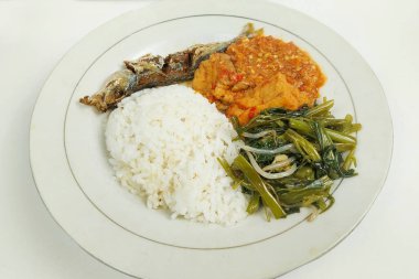 Kızarmış balık ve sebzelerle karıştırılmış pirinç beyaz bir tabakta, masanın üstünde.