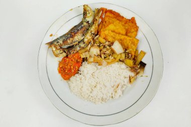 Kızarmış balık ve sebzelerle karıştırılmış pirinç beyaz bir tabakta, masanın üstünde.