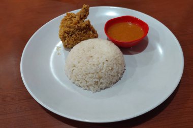 Çıtır tavuk, acılı sos ve beyaz pilav yemek masasında.