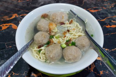 Masadaki beyaz kasede köfteli erişte.