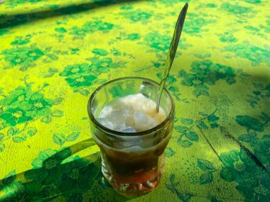 Cam bardaklarda buz ve yemek masasında kaşıklar.