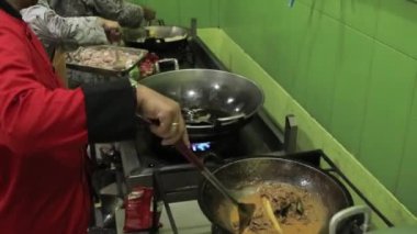 Bazı insanlar mutfakta kızartma tavası kullanarak yemek pişiriyor.