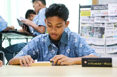 Makassar, Endonezya - 16 Temmuz 2024: Öğrenciler kütüphanede birlikte bir kitap okuyorlar