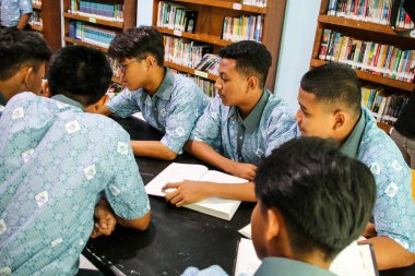 Makassar, Endonezya - 16 Temmuz 2024: Öğrenciler kütüphanede birlikte bir kitap okuyorlar