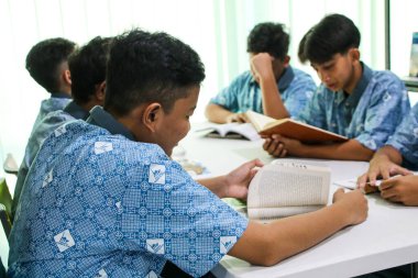 Makassar, Endonezya - 16 Temmuz 2024: Öğrenciler kütüphanede birlikte bir kitap okuyorlar