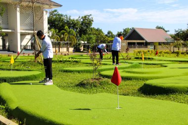 Makassar, Endonezya - 16 Temmuz 2024: İnsanlar güneşli bir günde mini golf oynuyorlar