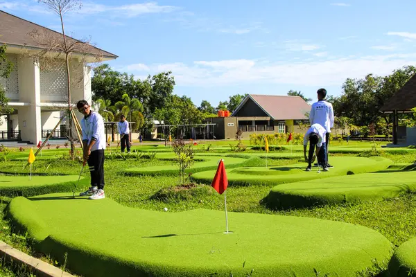 Makassar, Endonezya - 16 Temmuz 2024: İnsanlar güneşli bir günde mini golf oynuyorlar