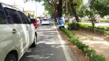 Makassar, Endonezya, 06 Ağustos 2024. Motosikletler ve arabalar şehrin ortasında trafiği geçiyor