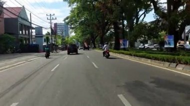 Makassar, Endonezya, 06 Ağustos 2024. Motosikletler ve arabalar şehrin ortasında trafiği geçiyor