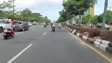 Makassar, Endonezya, 06 Ağustos 2024. Motosikletler ve arabalar şehrin ortasında trafiği geçiyor