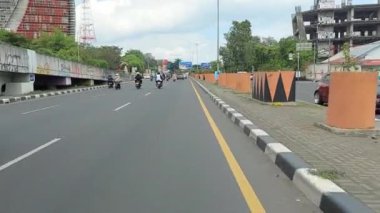 Makassar, Endonezya, 06 Ağustos 2024. Motosikletler ve arabalar şehrin ortasında trafiği geçiyor