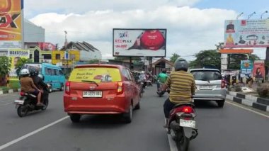 Makassar, Endonezya, 06 Ağustos 2024. Motosikletler ve arabalar şehrin ortasında trafiği geçiyor