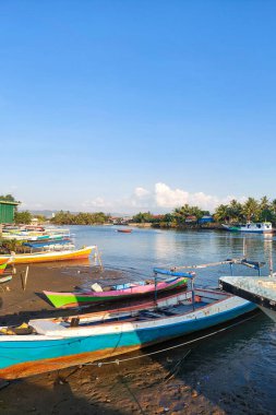 Tekneler nehir kıyısında arka arkaya park edilmiş.