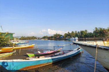 Tekneler nehir kıyısında arka arkaya park edilmiş.