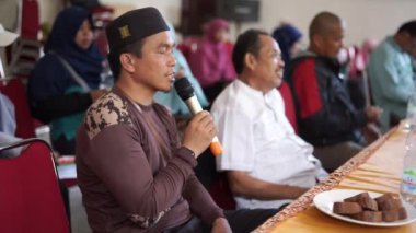 Endonezya, Makassar, 1 Kasım 2024. İnsanlar oturmuş mikrofon kullanarak sorular soruyorlar.