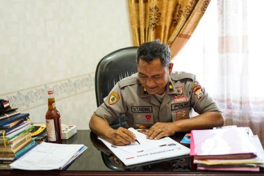 Endonezya, Makassar, 29 Kasım 2024. Masaya kitap yazan bir polisin portresi.