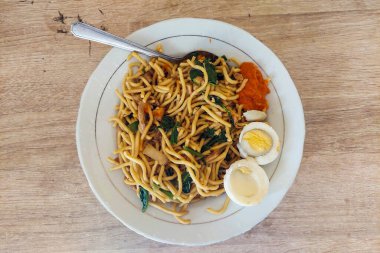 Beyaz bir tabakta erişte ve haşlanmış yumurta.