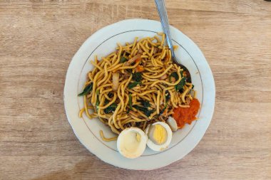 Beyaz bir tabakta erişte ve haşlanmış yumurta.