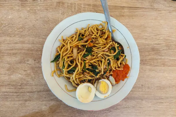 Beyaz bir tabakta erişte ve haşlanmış yumurta.