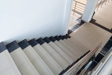 Beyaz seramik fayansları ve paslanmaz çelik tırabzanı olan kapalı merdiven.