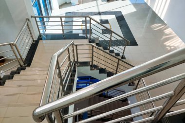 Modern merdiven seramik fayanslar ve parlak bir binanın içindeki paslanmaz çelik korkuluklar..