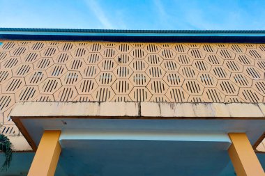 Altıgen şekilli geometrik duvar deseni ve berrak mavi gökyüzüne karşı havalandırma delikleri.