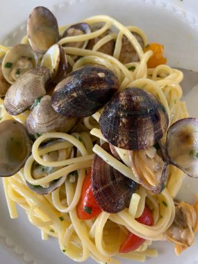 Masadaki beyaz tabakta istiridyeli, domatesli, maydanozlu ve sarımsaklı spagetti. Porno film.