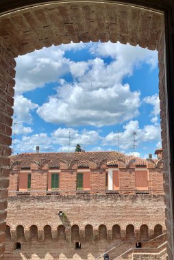 Mavi bulutlu gökyüzünün altında penceresi olan tuğla bir duvar görüntüsü