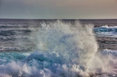 Deniz kıyısında büyük bir dalga, kayalıklarda kırılıyor