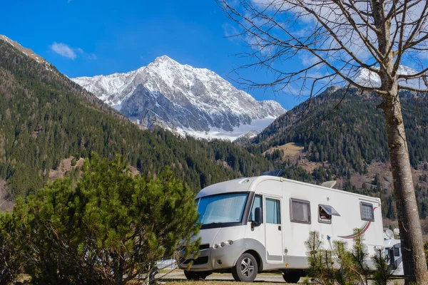 RV parked in a spring camping site set against the backdrop of the Dolomite Mountains, holiday trip in motorhome.