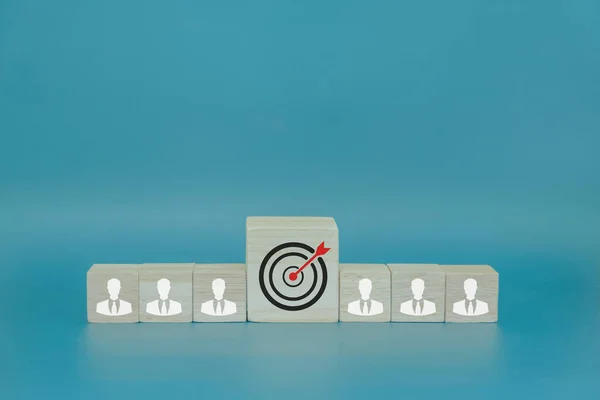 Businessman icon on wooden block and target icon in the middle, teamwork concept to bring success to the goal.