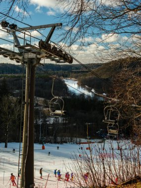 Sigulda 'da, sandalyeden görülebilen Gauja Nehri' nin zeminine uzanan karlı yamaçlardan kayakçılar inerken manzaralar sergiliyor ve kış macera atmosferini daha da güzelleştiriyor.