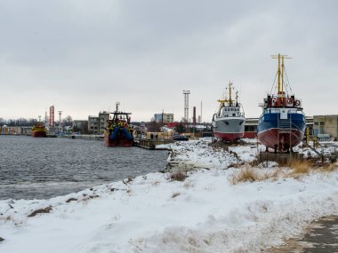 Soğuk bir kış gününün soğuğuna göğüs geren balıkçı tekneleri Ventspils kıyılarında dinleniyor. Renkli gövdeleri karlı zemine zıt düşüyor. Baltık Denizi 'ndeki uzun ömürlü deniz ruhunun bir kanıtı..