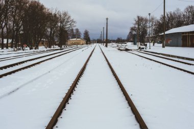 Ventspils 'te karlı bir kış gününün dingin sessizliğinin ortasında demiryolu rayları, el değmemiş beyaz manzaranın ortasında keşfedilmeyi bekleyen bir yola uzanıyor..