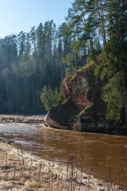 Nehir kenarında yürürken Amatas Dabas Taka 'nın gizli harikalarını keşfedin. Yükselen uçurumlar dramatik bir zemin oluşturur..