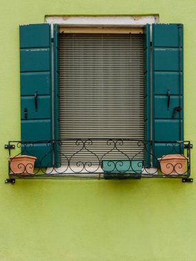 Soluk yeşil bir pencere, Burano 'nun canlı renklerinin arasında nazik ve yatıştırıcı bir varlık sağlar.